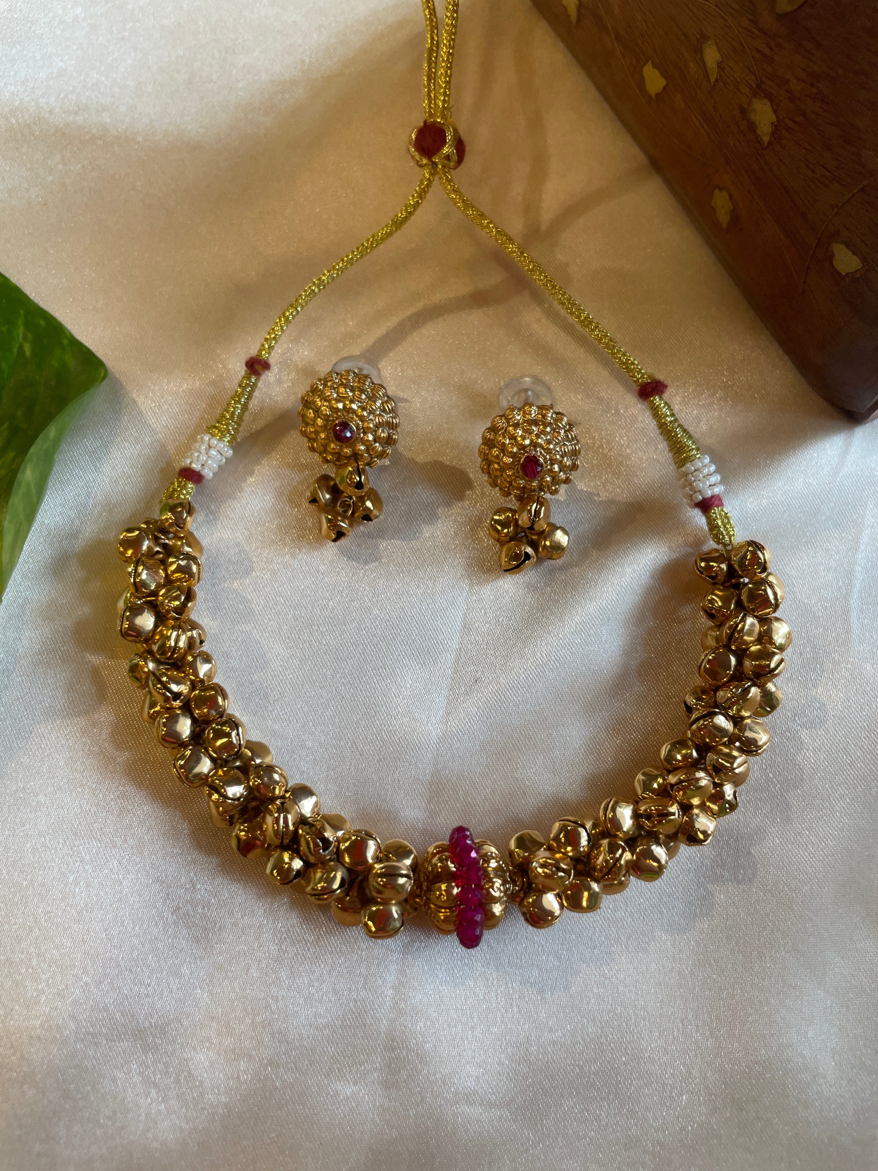 Chilanka-inspired gold microplated necklace featuring rounded bead detailing, ruby-toned centre accents and matching textured earrings