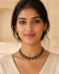 Kusuma gold-tone floral cluster choker with green stone details and matching floral stud earrings.
